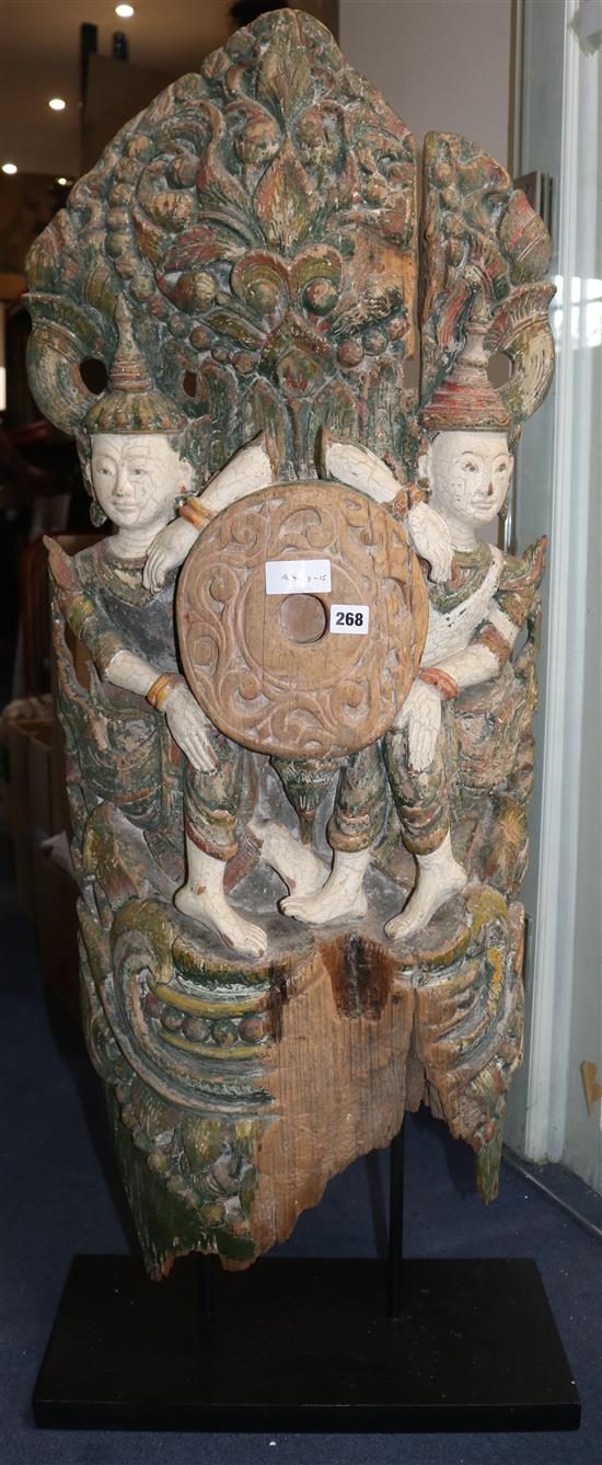 A carved wood fragment depicting two bodhisattvas holding a large circular disc between them, painted in green, white and red, height 1